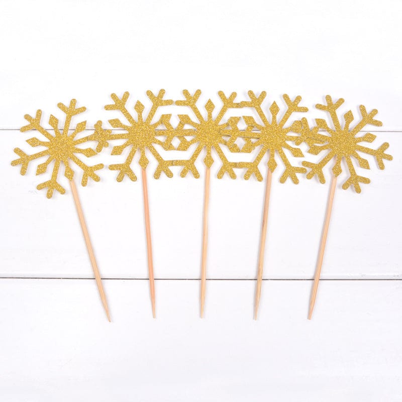 5 golden Snow flake cake toppers on counter