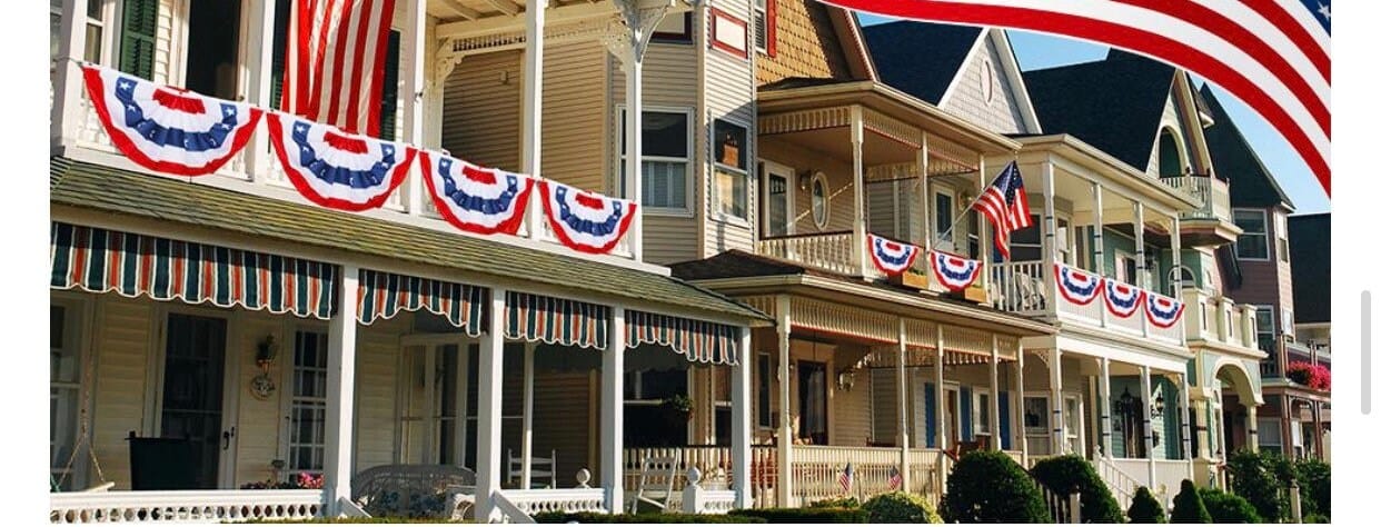pleated red white and blue bunting flags on upstairs front porch railings of 3 houses