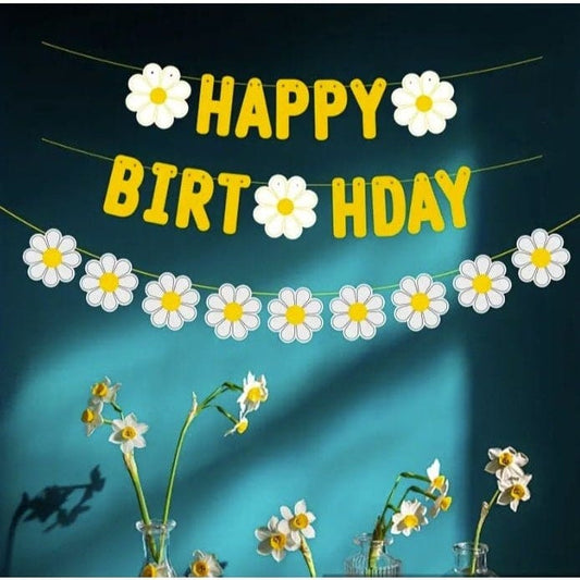 Yellow happy birthday banner hanging on wall with flowers under it