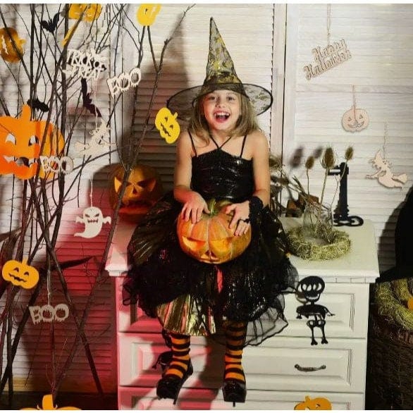 Girl in witch costume with wooden Halloween decorations hanging