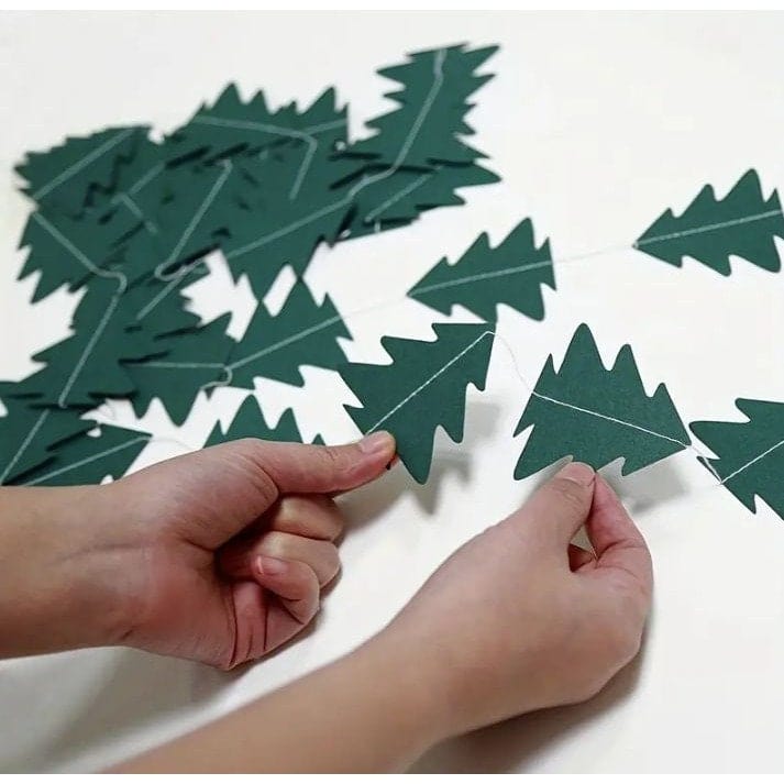 hands holding Mini Christmas trees sewed onto a string 