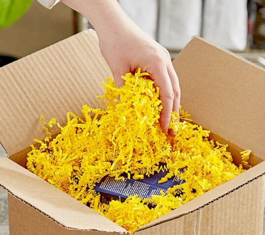 Yellow crinkle cut in a box with lady grabbing handful of it
